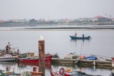 İnsanlar yelken ile balıkçı tekne ile Aveiro nehri görünümü. Tipik bitki örtüsü ve binalar ile bulutlar ve arka plan ile Gün