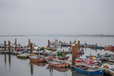 Özel eğlence tekneleri ve balıkçı tekneleri ile Aveiro nehir ve marina manzarası. Bulutlar ve arka plan ile Gün