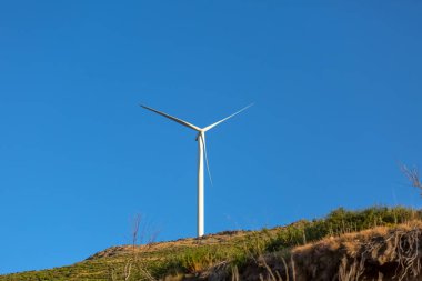 Dağların tepesinde bir rüzgar türbini, Portekiz 'de arka plan olarak mavi gökyüzü