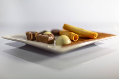 Beyaz tabaktaki lezzetli şekerlerin ayrıntılı görüntüsü, gölgeli beyaz arka plan.