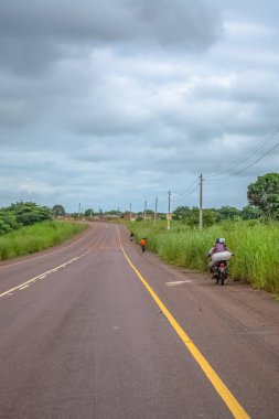 Malange / Angola - 12 08 2018: Tipik asfalt yolu manzarası, kenarda yaşayan insanlar, tipik tropikal manzaralar, ağaçlar ve diğer bitki örtüleri