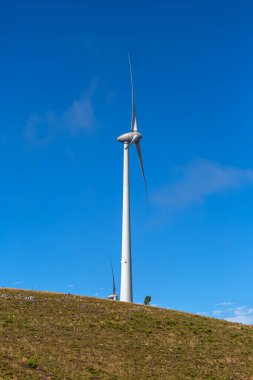 Dağların tepesinde bir rüzgar türbini, Portekiz 'de arka plan olarak mavi gökyüzü