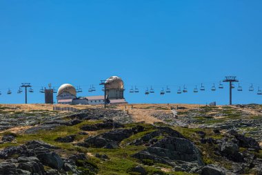 Seia / Serra da Estrela / Portugal - 08: 15 2020: Serra da Estrela doğal parkının zirvesine, kubbeli ve teleferikli kule binalarına, Star Mountain Range 'e, kayalara ve bitki örtüsüne ve dağ manzarasına bakın