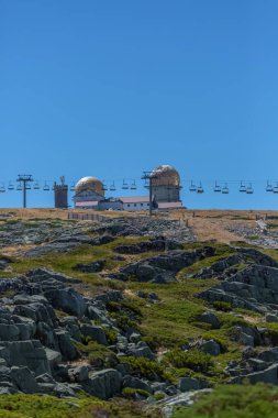 Serra da Estrela doğal parkının dağlarının tepesine bakın, kubbeli ve teleferik tramvaylı kule binaları, Star Mountain Range, kayalar ve bitki örtüsü ve dağ manzarası