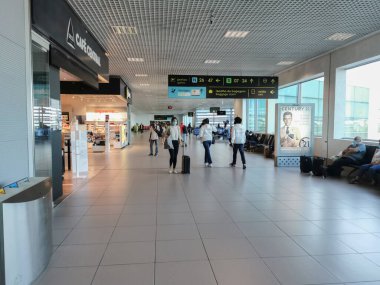 Lizbon / Portekiz 09 25 2020: Lizbon havaalanı binasının iç manzarası, bavullar ve çantalarla yürüyen ve kalkış noktasındaki koridorda dinlenen koyu renkli maskeli insanlar