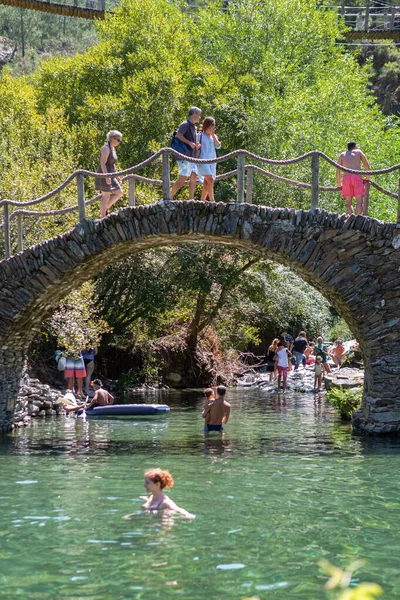 Piodao / Arganil / Portekiz - 08 22 22 2020: Piodao köyündeki doğal havuz manzarası, foz da egua, schist üzerindeki köprü, ziyaret eden turistler ve güneşlenen ve yüzen insanlar