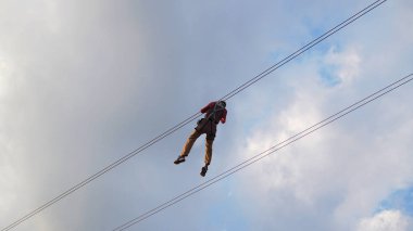 Zip hattını gökyüzü arka plan ile oynayan bir adam.