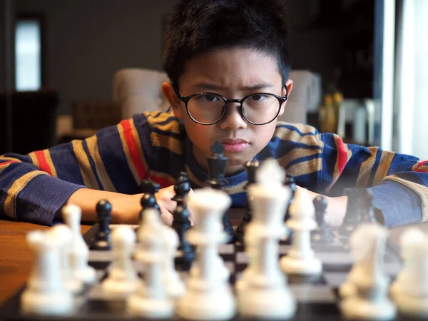 Menino asiático jogando xadrez na mesa em casa. (foco selecionado ) — Fotografia de Stock