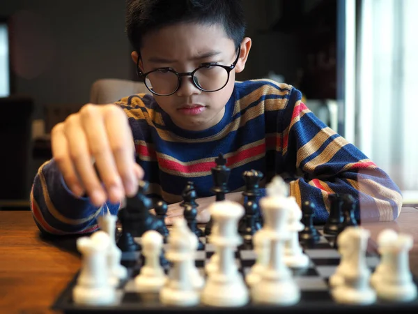 Menino asiático jogando xadrez na mesa em casa. (foco selecionado ) — Fotografia de Stock
