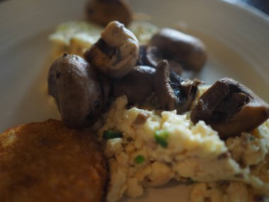 Çırpılmış yumurta, sosis, haşhaş kahverengi ve mantar ile kahvaltı tabağı closeup. Seçili odak.