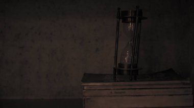 Eski kitapların üstünde karanlıkta kum saati veya saat cam Closeup. Seçili odak.