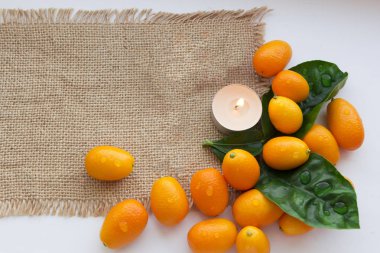 Çuval bezi üzerinde kumquats ve mumlar natürmort. Rahatlatıcı arka plan. Spa tasarımı için arka plan.