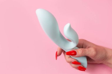 the Dildo in hand on a pink background, sex toy
