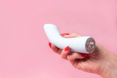 the Dildo in hand on a pink background, sex toy