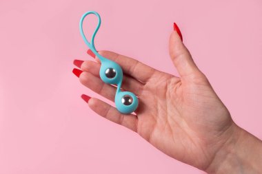 the Dildo in hand on a pink background, sex toy