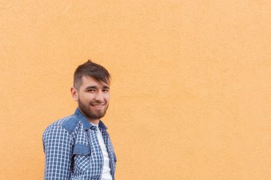 Turuncu duvara yaslanmış güzel ve mutlu adam.