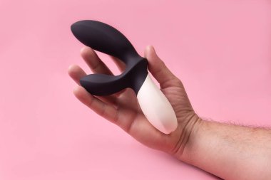 the Dildo in hand on a pink background, sex toy
