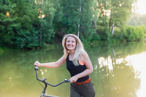 the Happy woman with a bike by the river