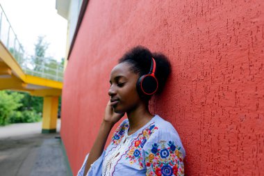 Afro-Amerikalı bir kadın sokakta kulaklıkla müzik dinliyor.