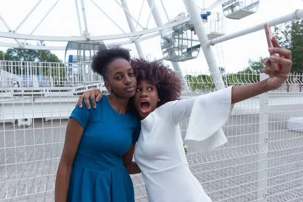 İki Afro-Amerikalı kadın parkta dans ediyor.