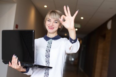 Güzel ve mutlu sarışın bir dizüstü bilgisayarın elinde.