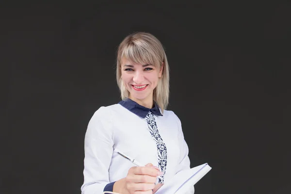 the Happy blonde, teacher against the background of the black wall