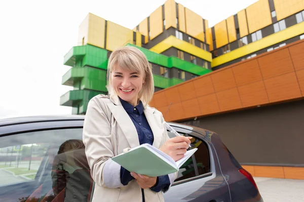 Arabasının yanında not defteri olan mutlu kız.