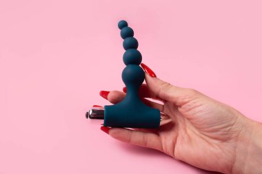 the Dildo in hand on a pink background, sex toy