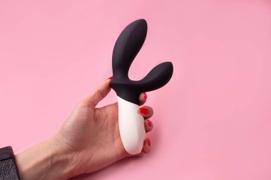 the Dildo in hand on a pink background, sex toy