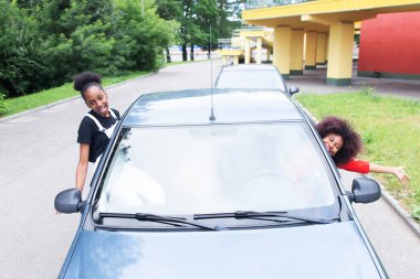 İki Afrikalı Amerikalı kadın arabada eğleniyor.