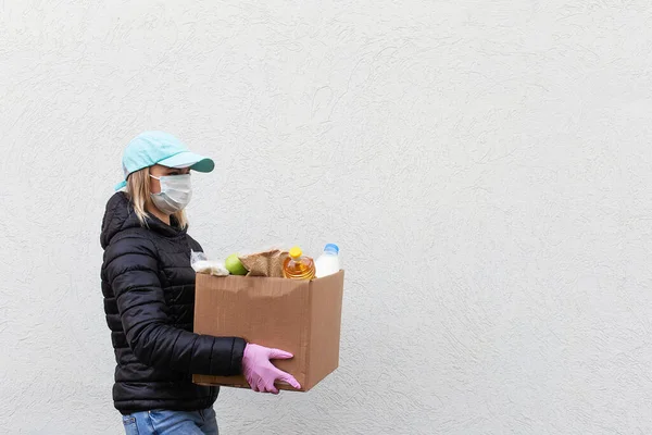 the Girl volunteer in protective mask with food box, donation