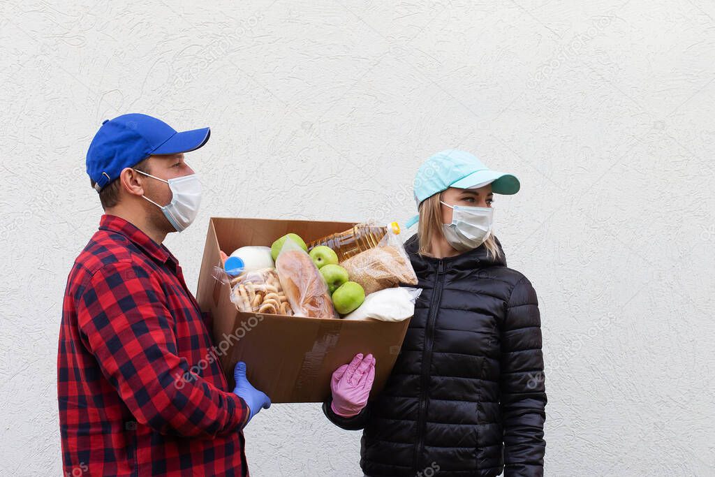 the volunteers in protective masks with a box of food