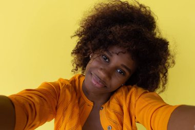 Mutlu Afrikalı Amerikalı sarı arka planda selfie çekiyor.