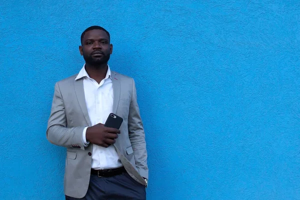 the African American with phone against blue wall