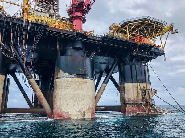 Semi submersible drilling rig view from crew vessel\'s deck. Rig deballasted so legs can be seen at all heights including the anchor rack