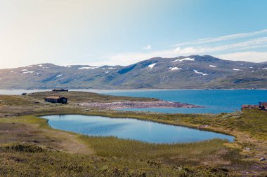 Oppland, Norveç için Jotunheimen Milli Parkı manzara. Eski geleneksel Norveç kulübe bir dağ Gölü ve arka planda bir dağ deniz kenarı.