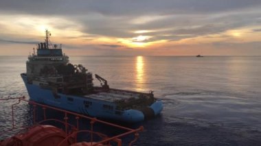 Petrol sahası destek gemisi gün doğumunda sondaj kulesine yakın manevra