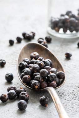 Gri yapının arka planında, ön planda, ardıç meyveli bir kaşık.