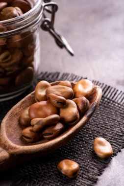 Cam kavanozda kurumuş fasulye ve ön planda tahta kaşık.