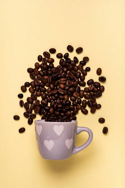 top view, from coffee cup with heart, coffee beans pour isolated on a yellow background, love and passion for coffee.