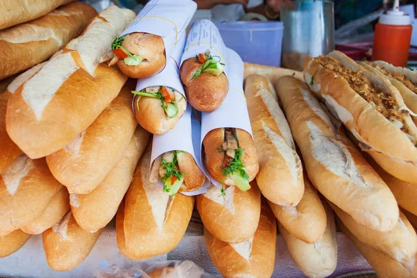 Still life. Laos style breakfast. Baguette or French bread with tomatoes, cucumber, spring onion, and vietnamese pork sausage in paper rolls. — Stock Photo, Image