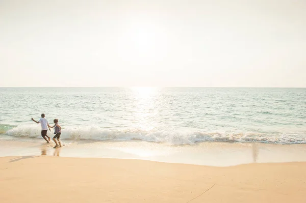 Tiempo de vacaciones. Niños felices jugando en la playa de arena al atardecer — Foto de Stock