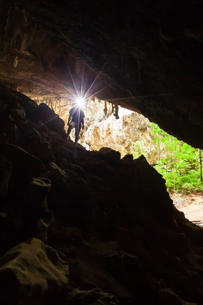 Νέος άνθρωπος εξερευνώντας μυστηριώδη σπηλιά με ένα δαυλό. — Φωτογραφία Αρχείου