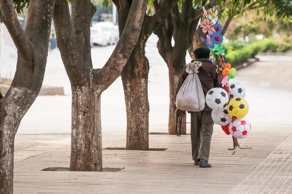 Hombre mayor chino vendedor ambulante bola vendedor y otros juguetes en la calle . — Foto de Stock