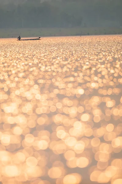 Un pêcheur asiatique sur le lac lumineux au coucher du soleil . — Photo