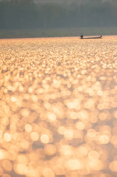 Egy ázsiai Halász az izzó tó naplementekor. — Stock Fotó