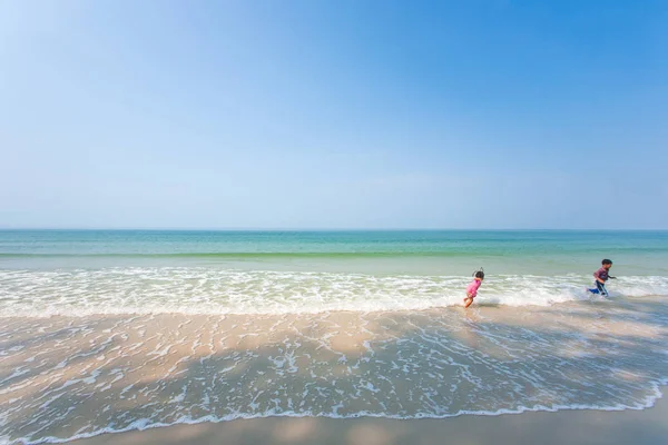 Feliz hermano mayor y hermana pequeña jugando en el mar azul . — Foto de Stock