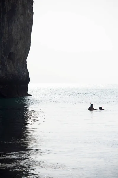 Pareja de turistas haciendo snorkel en el mar frente a un antiguo acantilado . — Foto de Stock