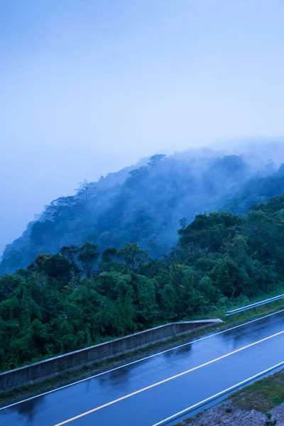 Estrada de montanha no crepúsculo nebuloso, estrada de asfalto através da montanha t — Fotografia de Stock
