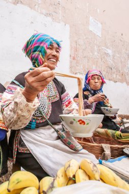 Taze meyve ve sebze satarken erişte yiyen Çinli bir grup son sınıf kadın satıcı..
